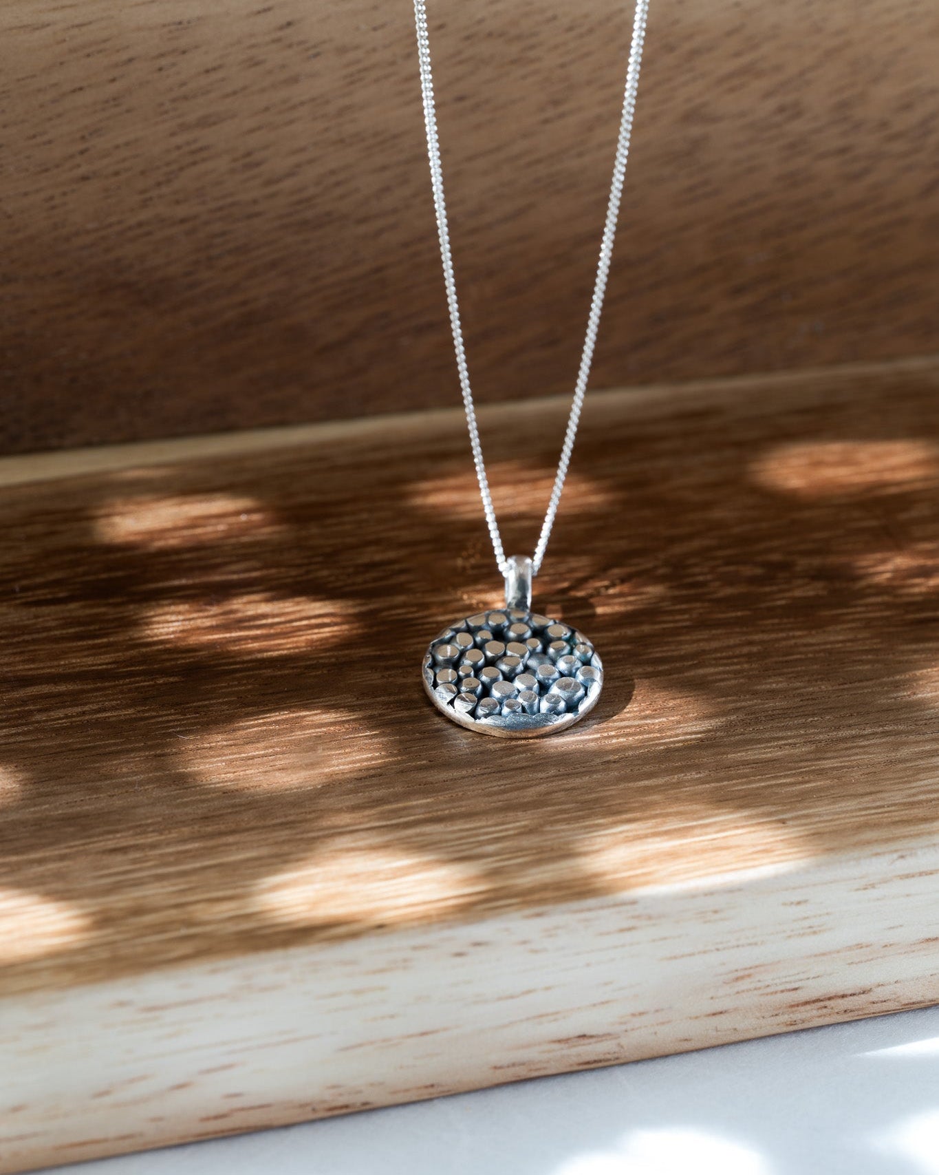 Silver necklace with a pendant on a wooden surface