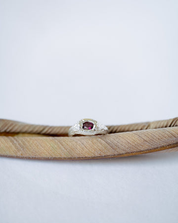 Silver ring with a red gemstone on a white background