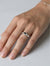 Hand wearing a silver ring with a black gemstone on a light gray background