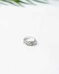 Silver ring with green gemstones on a white background