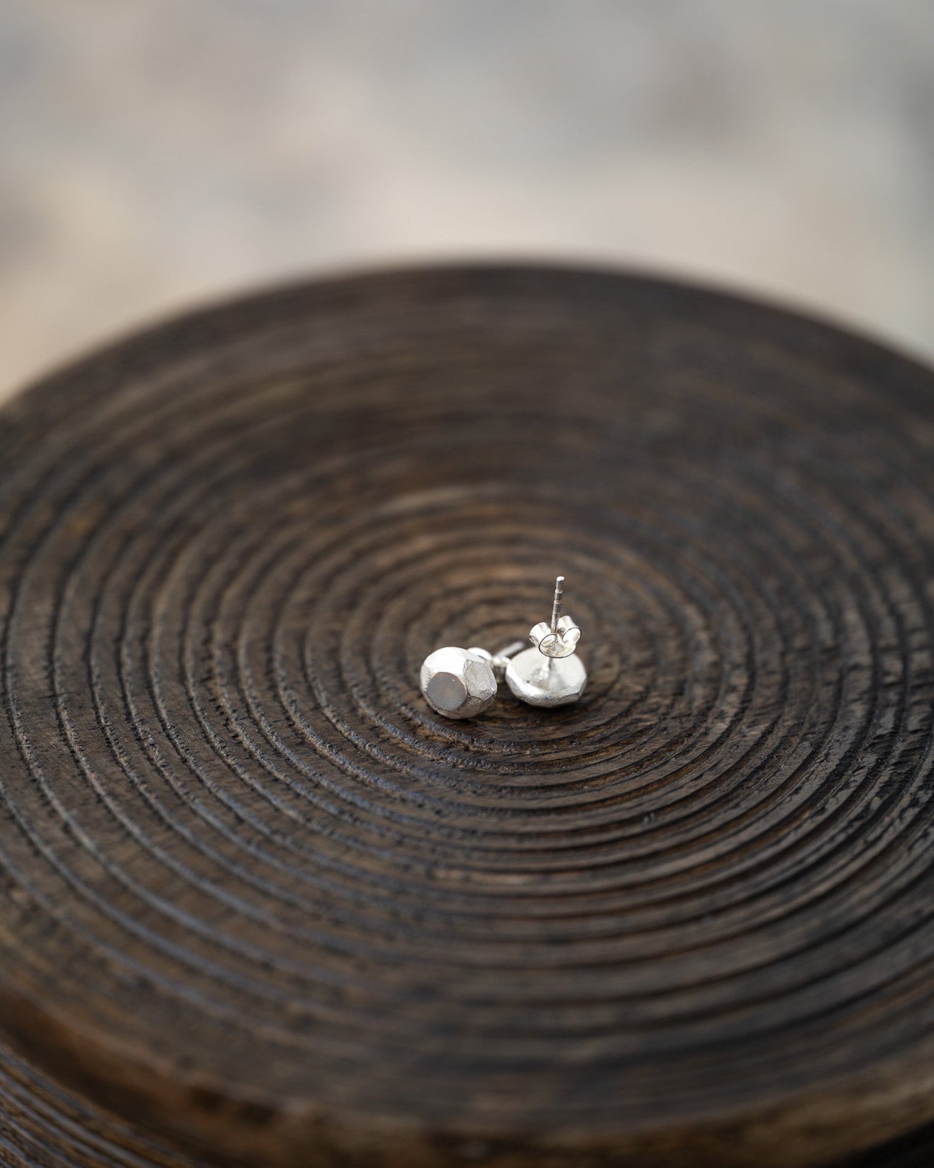 Pair of silver earrings on a textured wooden surface
