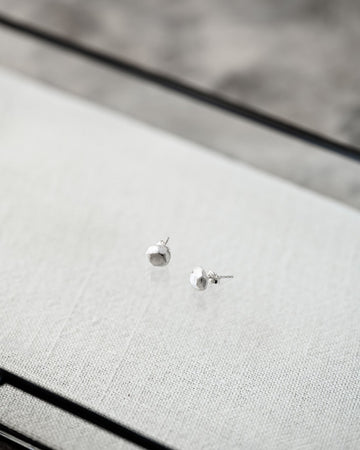 Silver stud earrings on a textured gray surface