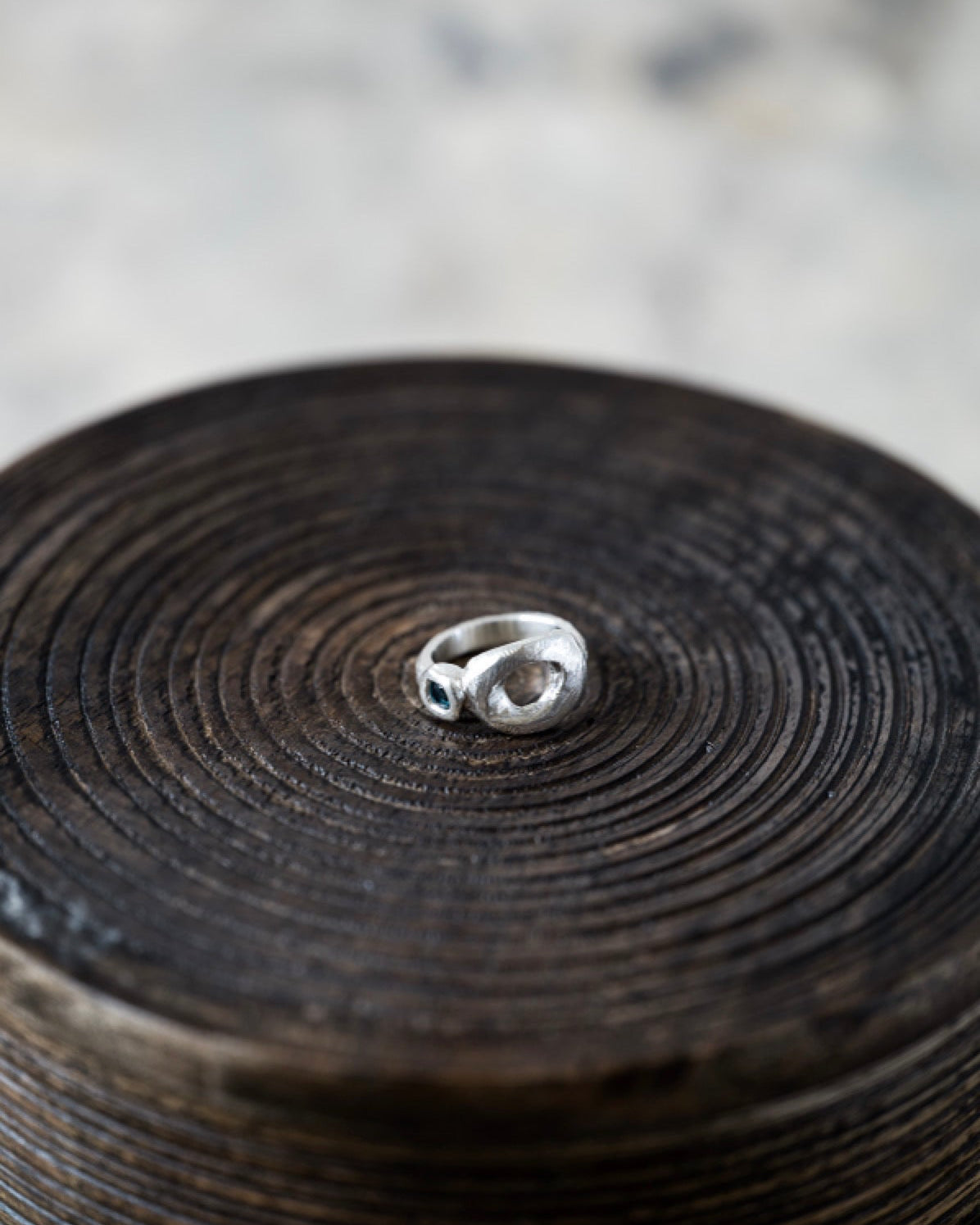 Silver ring on a textured wooden surface with a blurred background