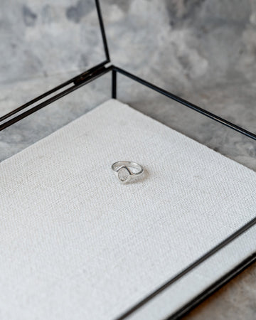 Silver ring in a glass display case on a textured surface