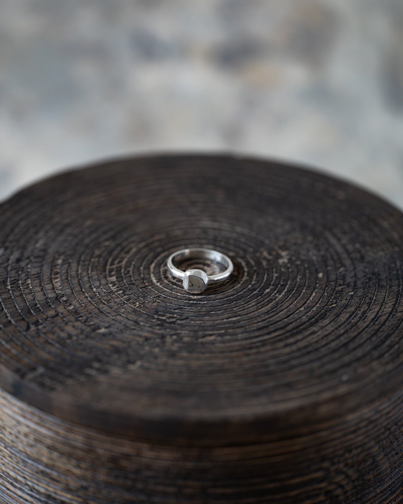 Silver ring on a textured wooden surface with a blurred background