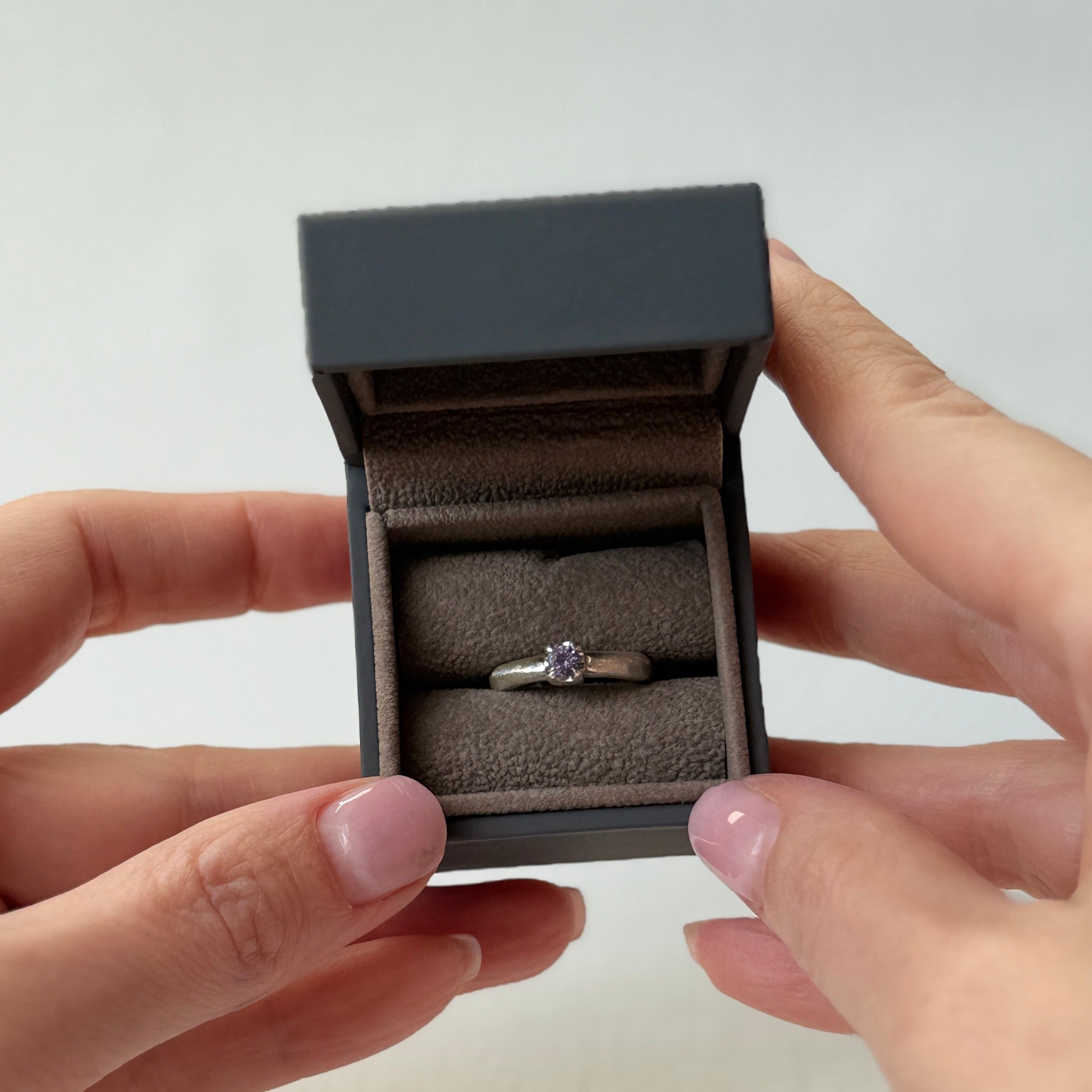 Ring in a small black box held by hands on a light background