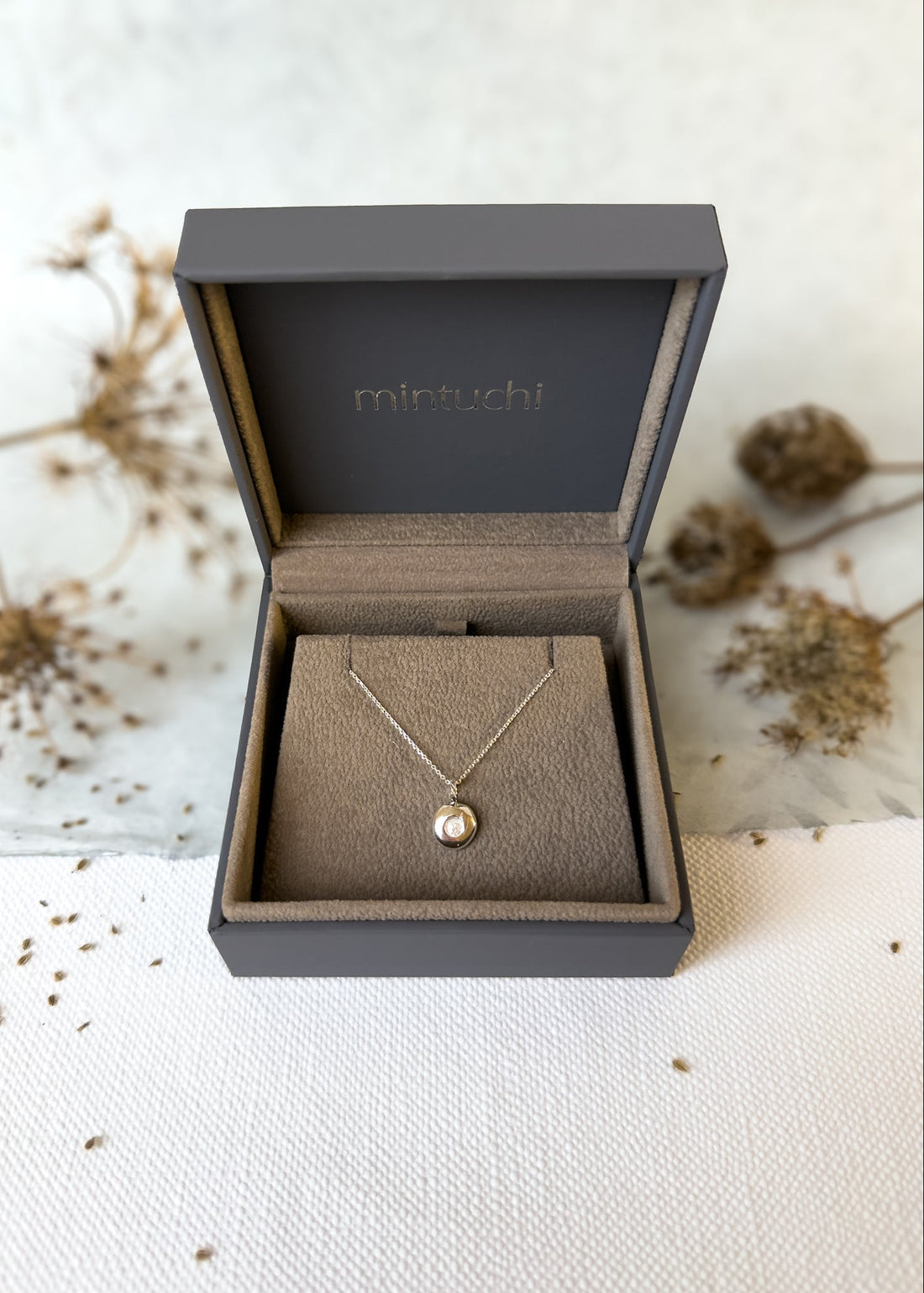 Necklace with a pendant in a black jewelry box on a textured surface