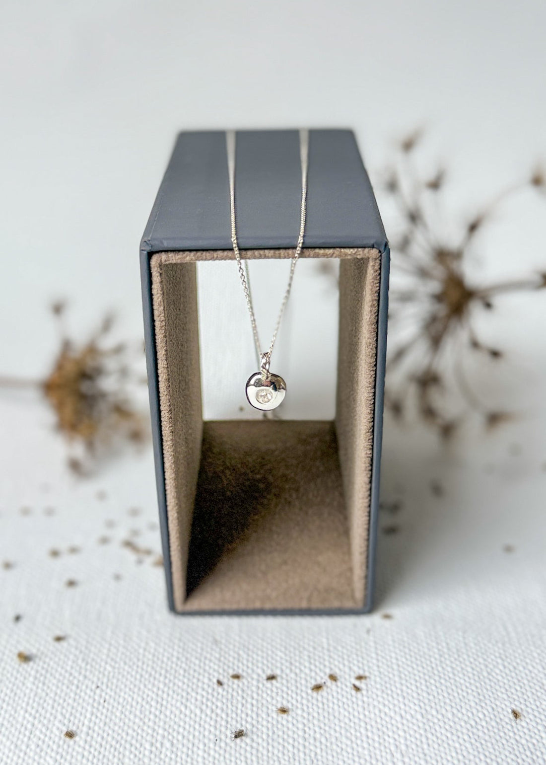 Necklace with a pendant in a black jewelry box on a textured surface