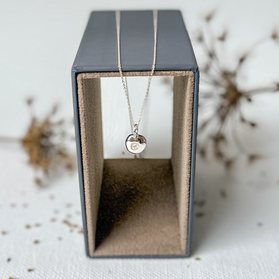 Necklace with a pendant in a black jewelry box on a textured surface