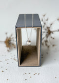 Necklace with a pendant in a black jewelry box on a textured surface