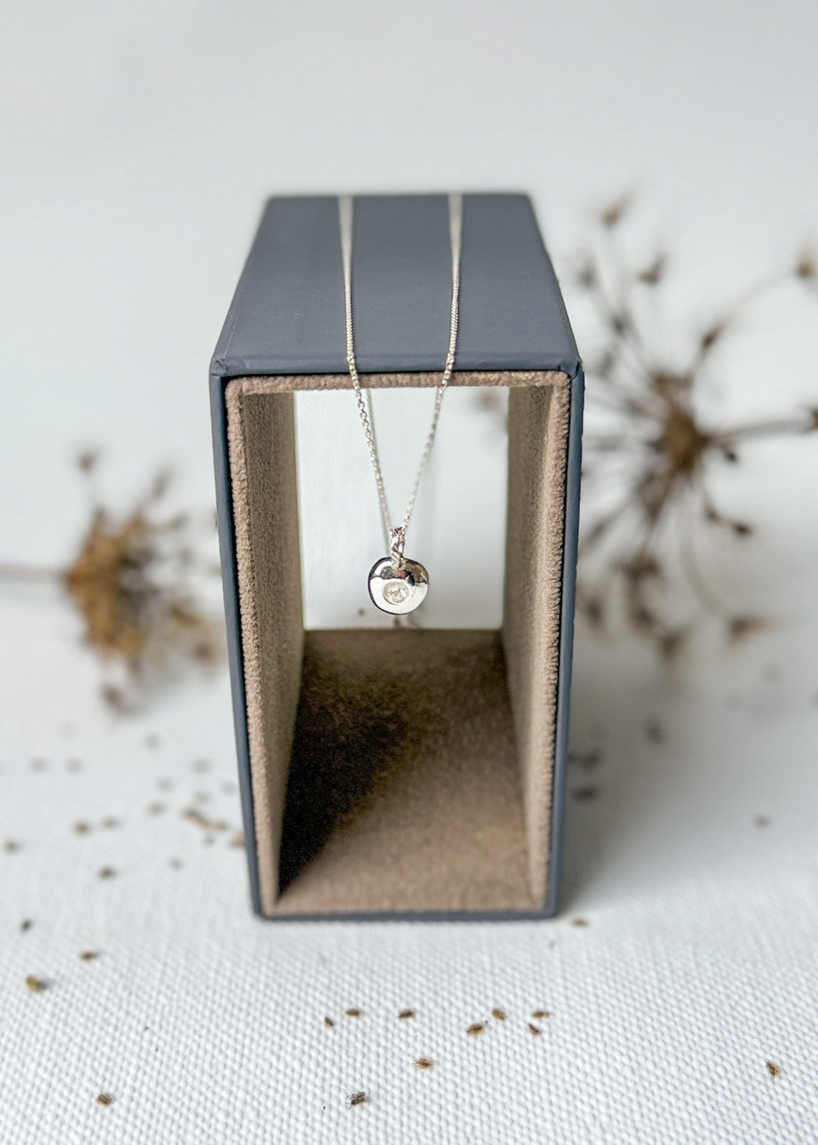 Necklace with a pendant in a black jewelry box on a textured surface
