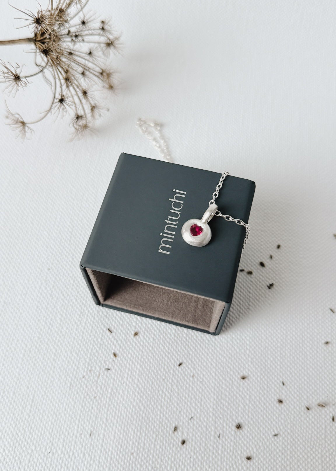 Necklace with a red gemstone in a 'minuichi' box on a light background