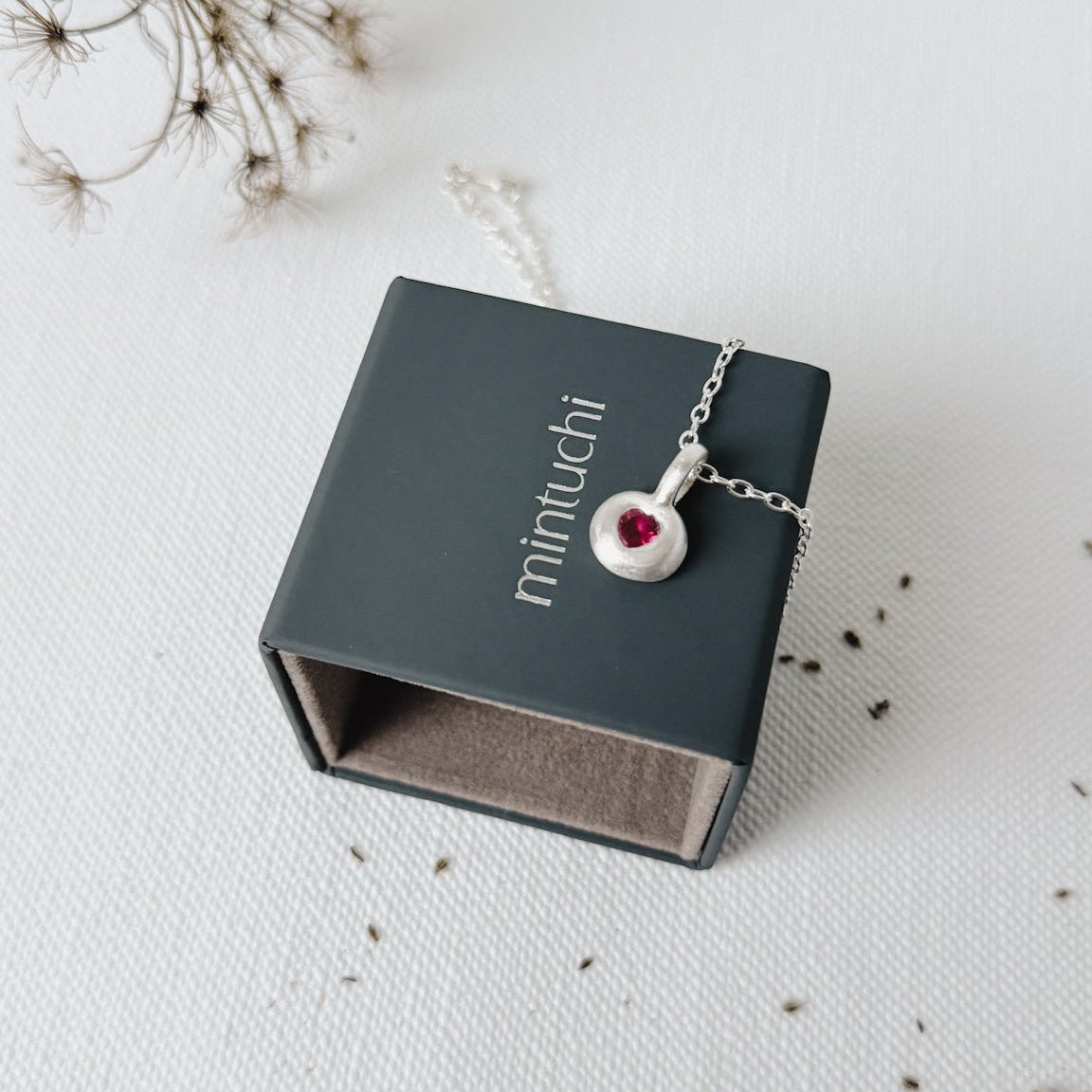 Necklace with a red gemstone in a 'minuichi' box on a light background