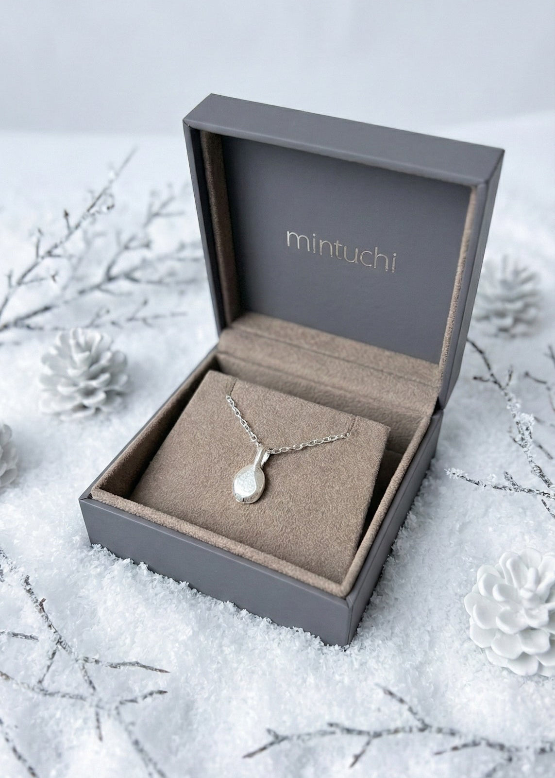 Silver necklace in a 'mintuchi' box on a snowy background