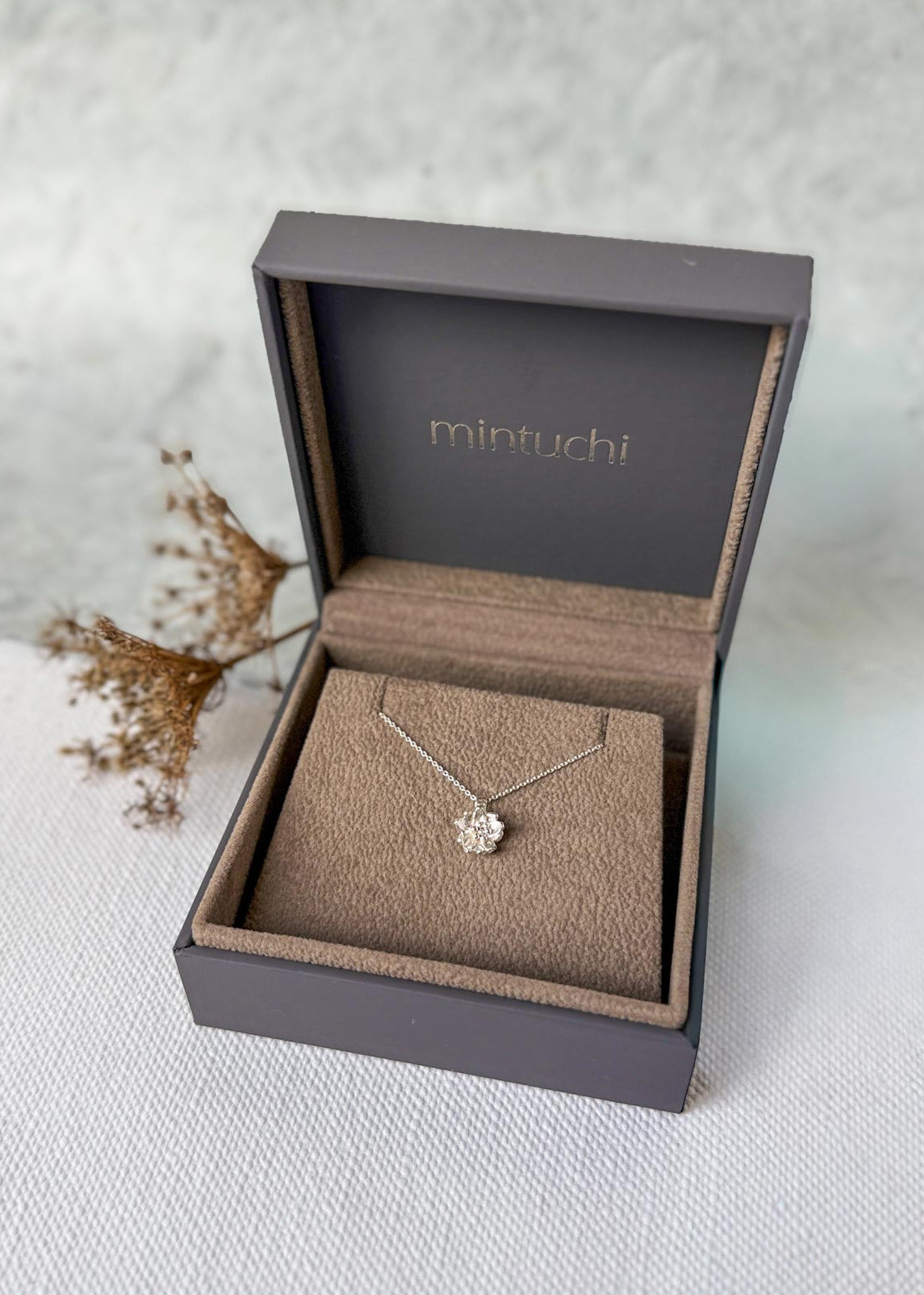 Silver necklace in a 'mintuchi' branded box on a light background