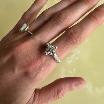 Hand wearing two rings with a plain background