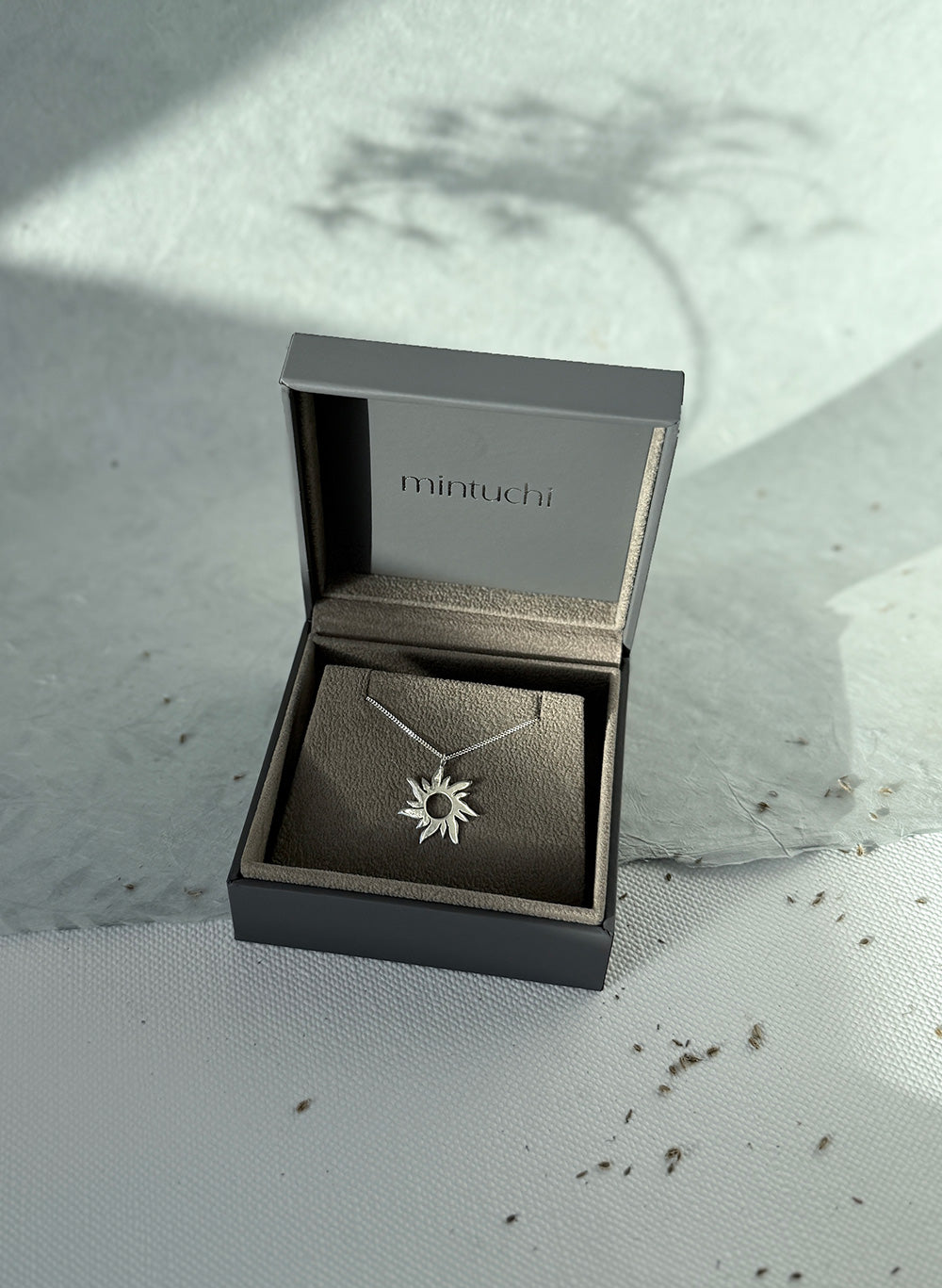 Necklace with a star pendant in an open jewelry box on a textured surface